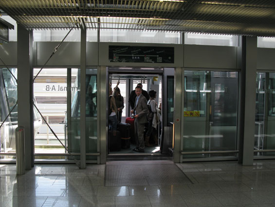 Nástup do letištního vláèku "Sky Train" se dìje dveømi v oddìlovací sklenìné stìnì. Trasa závìsné dráhy má 4 stanice, jízdní doba je cca 7 minut.