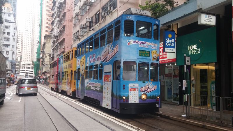 Žádný jednotný nátìr hongkongských tramvají neexistuje – všechny jsou opatøeny celovozovou reklamou. Zde odpoèívají na nejzápadnìjší koneèné Kennedy Town, kam byla nedávno prodloužena také zatím jediná ostrovní linka metra.