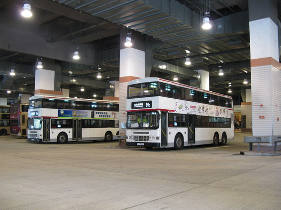 Starší bílé autobusy nejvìtšího dopravce KMB na koneèné stanici hnìdé linky metra Wu Kai Sha daleko za centrem mìsta.