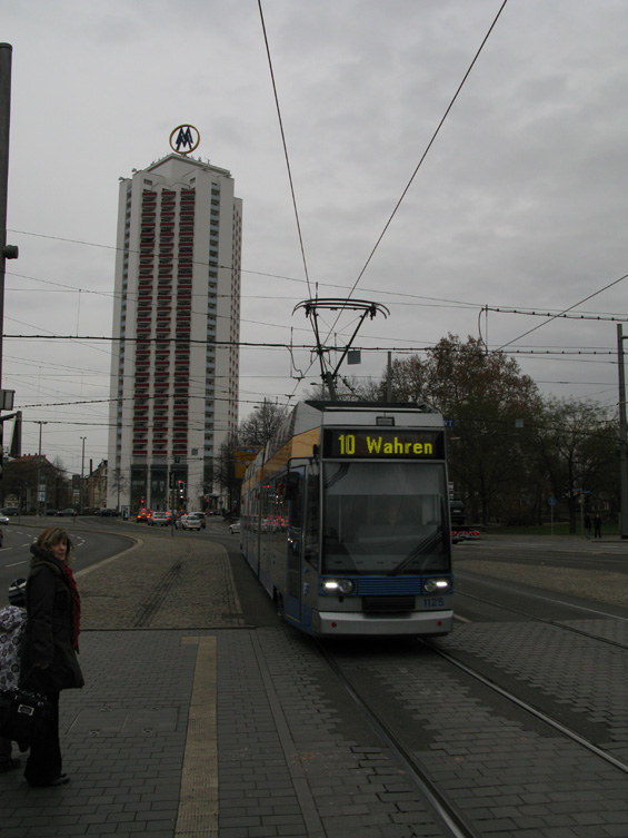 Tøídílná èásteènì nízkopodlažní tramvaj na lince 10 pøijíždí na hlavní nádraží kolem dalšího z lipských mrakodrapù.