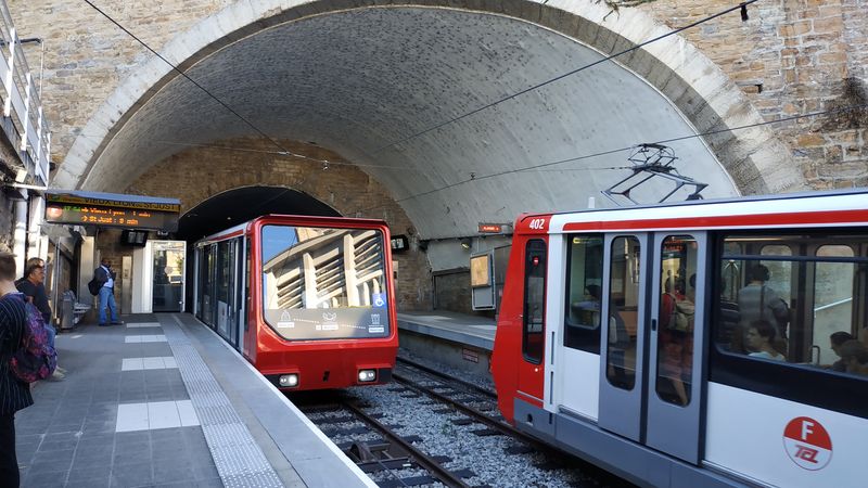Setkání dvouvozových lanovek v mezilehlé stanici Minimes. Obì koneèné stanice lanovky Vieux Lyon – Saint-Just jsou skryté v podzemí. V první polovinì roku 2019 probìhla modernizace této lanovky – vozy dostaly také nový nátìr.