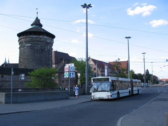Starší naftový autobus MAN v pozadí s hradbami kolem historického centra.