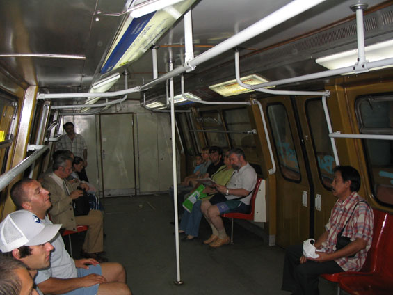 Interiér rumunského vozu metra. Soupravy jsou širší a díky ménì sedaèkám i kapacitnìjší. Informace i reklamy jsou umis�ovány pøímo na záøivkové osvìtlení.