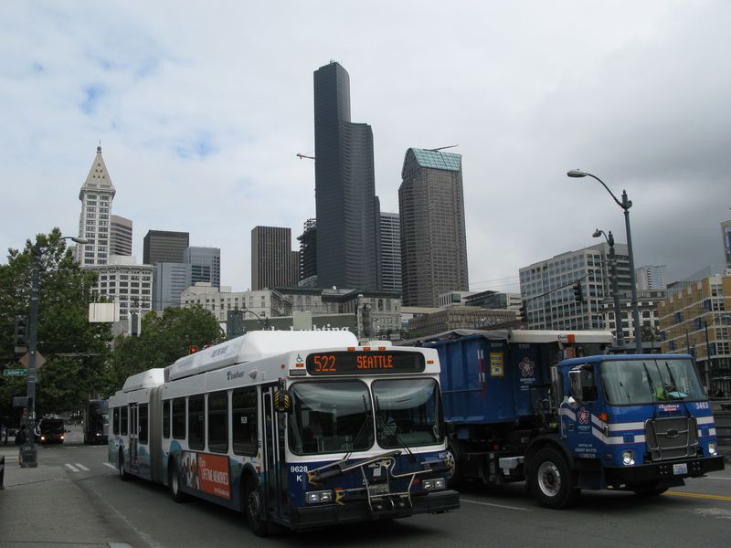 Starší kloubový pøímìstský autobus v centru Seattlu v pozadí s typickými výškovými budovami. Poblíž se nachází také historická budova vlakového nádraží „King Street“, kam se ráno sjíždìjí „dìlnické“ dvoupatrové vlaky a odpoledne se rozjíždìjí zpìt na sever a na jih.