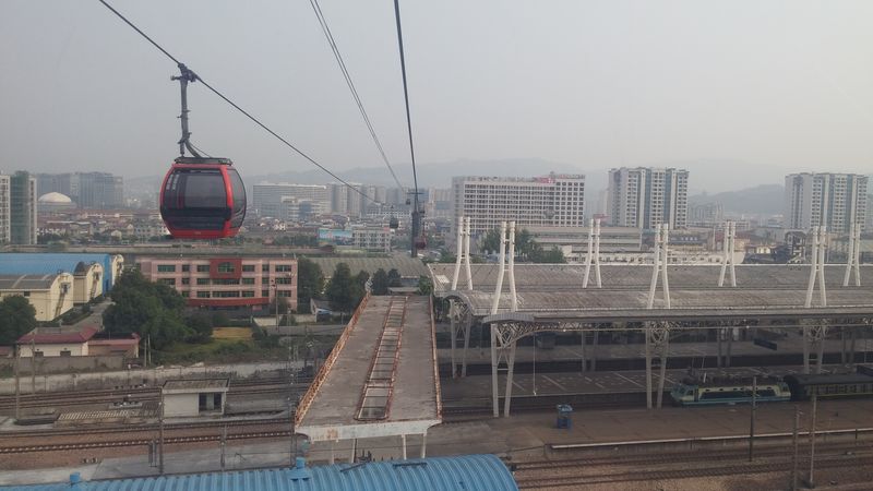 A zde už údajně nejdelší horská lanovka na světě stoupá nad nástupišti vlakového nádraží v Zhangjiajie směrem na náhorní plošinu Tianmen. Lanovka je dlouhá cca 7,5 km a zdolává převýšení cca 1300 m. Na rychlé a někdy až závratně strmé trase je provozováno celkem 98 kabinek.