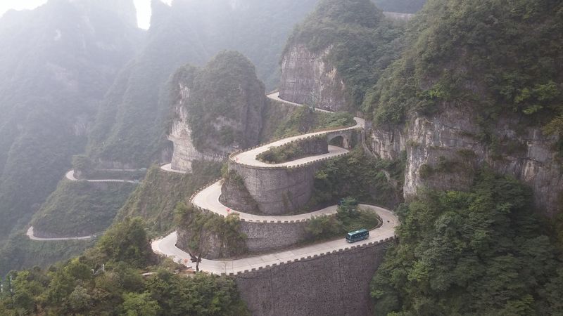 K náhorní plošině v národním parku Tianmen vede kromě lanovky také tato silnice s 99 zatáčkami. Jezdí po ní výhradně zelené parkové mikrobusy, které vozí turisty k úpatí obřího schodiště, od kterého pak pokračuje nahoru soustava eskalátorů.